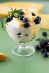 Dessert parfait of yogurt melon and blueberries on a green background