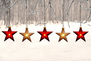 Five star-shaped Christmas ornaments, three red and two glowing gold, hang from frosted branches. Concept of Christmas decorations, holiday season, festive, winter, celebration.