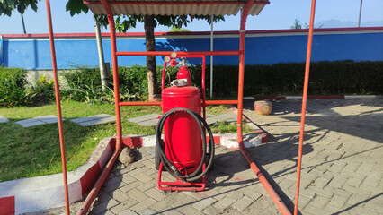 Fire extinguisher with black hose standing outside on the street, Red metal mobile portable fire...