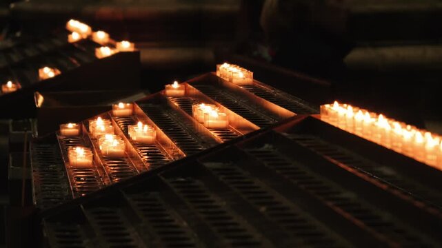 Candles illuminate the interior of church, creating a serene atmosphere with warm, flickering light that reflects the spiritual ambiance and relaxation. High quality 4k footage