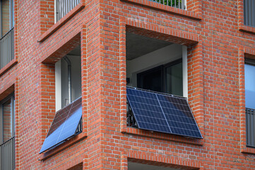 Modern brick apartment with balcony solar panels for sustainable urban living. Solar panels mounted...