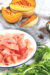 salad ingredients, prosciutto and melon, arugula and basil, mozzarella cheese, balsamic sauce, close-up,