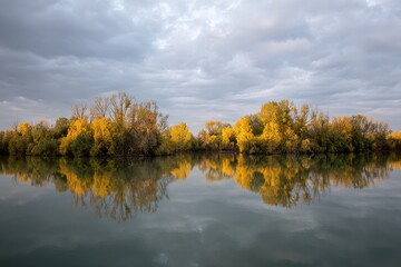 Fototapeta premium Calm autumnal river scene with mirrored trees