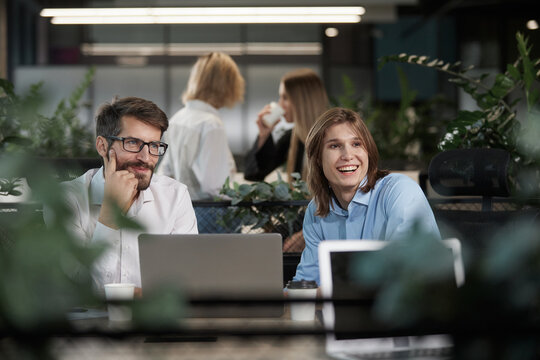 A group of people are sitting around a table with a laptop open