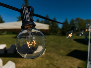 A bright and radiant light bulb, expertly suspended from a meticulously arranged string of...