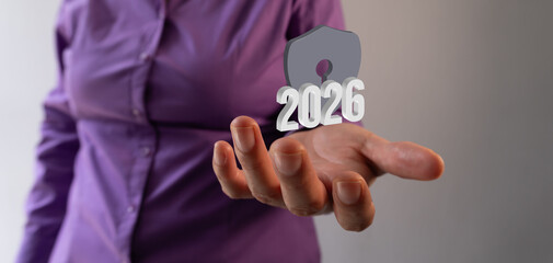 Businesswoman manipulating a digital symbol in the air of a 3D shield and the year 2026