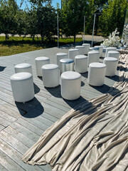 A stylish row of white ottomans is elegantly placed on a sturdy wooden deck, creating a comfortable...