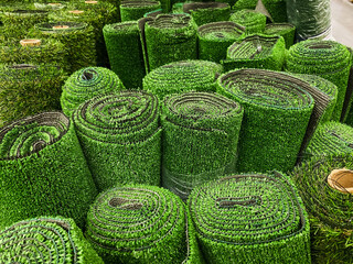 A large collection of rolls of vibrant green grass are neatly stacked on top of each other,...