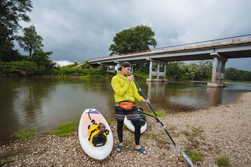 An Adventurous StandUp Paddleboarder, Decked Out in a Bright and Vibrant Yellow Jacket, Fondly...