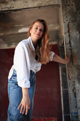 Naklejka premium A model wearing a white shirt and blue jeans stands on a piano in a studio. The soft lighting highlights the curves of the piano and creates an exquisite atmosphere, perfect for luxury and fashion