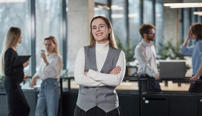 A woman in a gray vest stands in front of a group of people