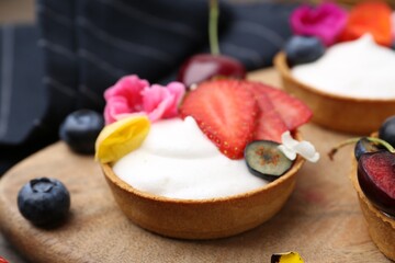 Sweet tartlets with berries and flowers on table, closeup. Delicious dessert