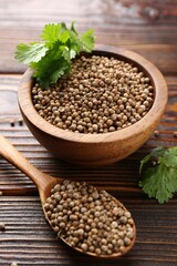 Coriander seeds and fresh cilantro leaves on wooden table, closeup