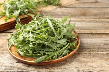 Fresh ripe green arugula leaves on wooden table, closeup. Space for text