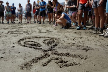 Crowd Gathers Around Alien Drawings on the Beach During a Summer Festival Event