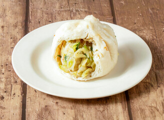 Steamed Bun with Savory Vegetable and Meat Filling on a Rustic Wooden Table in plate side view of taiwan food