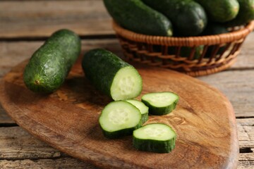 Cut and whole cucumbers on wooden table, closeup