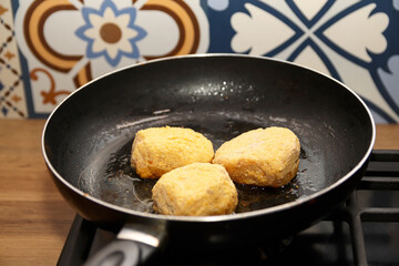 A scratched frying pan with delicious, semi-finished cutlets, symbolizing quick and easy food preparation in a busy kitchen