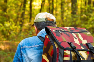 A man with a big backpack is walking through an autumn forest in Espoo, Finland. This scenic image captures the spirit of wanderlust and travel in the Scandinavian landscape