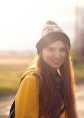 a happy, young woman in her 20 years, wearing a yellow raincoat and a hat, with a gentle smile. The image, with a vintage film grain effect, captures a moment of relax in an autumn forest