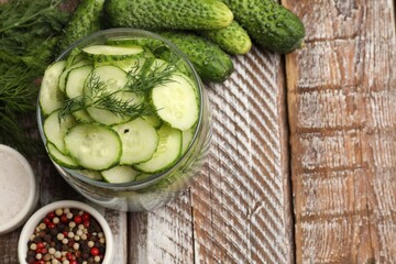 Making pickles. Slices of fresh cucumbers in open jar, spices and dill on color wooden table, flat lay