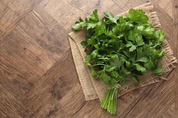 Bunch of fresh parsley on wooden table, top view. Space for text
