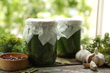 Making pickles. Fresh cucumbers in jars and spices on wooden table outdoors, closeup
