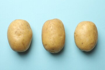 Fresh raw potatoes on light blue background, top view