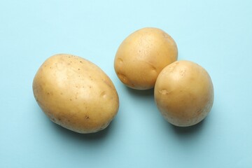 Fresh raw potatoes on light blue background