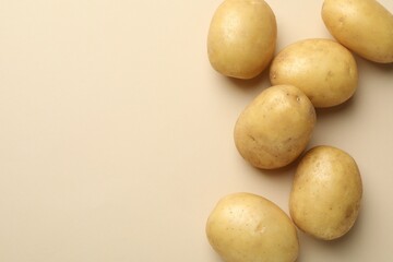 Fototapeta premium Fresh raw potatoes on beige background, top view. Space for text