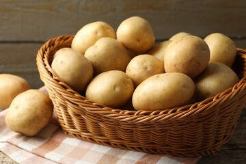 Fresh potatoes in basket on wooden table, closeup