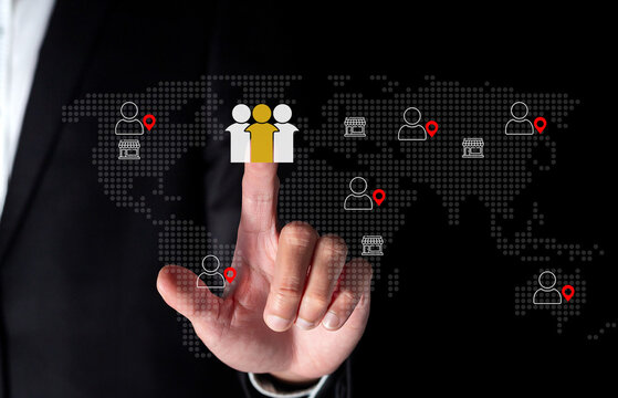 Global workforce management concept. Businessman selects digital user icon on world map interface, symbolizing remote team connection, HR analytics, recruitment, and talent location tracking.