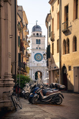 Padua astronomical clock tower Torre dell'Orologio behind a historic Italian city alley leading to Piazza dei Signori in warm summer afternoon sun