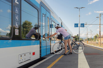 A cyclist boards a train with their bicycle at a station, showcasing convenient transportation options. © 24K-Production