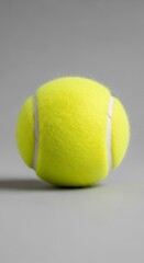 Yellow tennis ball against a gray background.