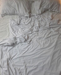 Soft white bedding with rumpled sheets and pillows creating a cozy and inviting atmosphere