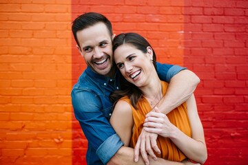 Happy Couple Embracing in Front of Colorful Brick Wall