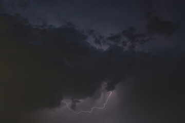 Dark, dramatic storm clouds gather on the horizon, hinting at an approaching thunderstorm. The sky...