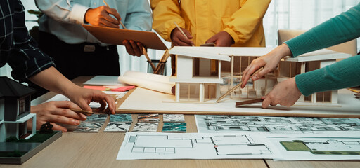 A dynamic architectural design meeting showcases professionals collaborating over blueprints and a...