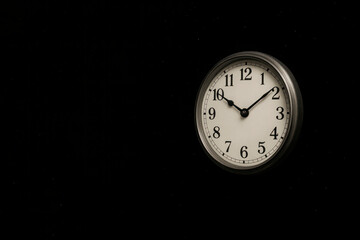 Wall clock on a black background with an empty space on the left. Space for text.