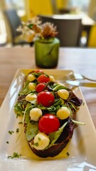 Healthy rye bread toast with mozzarella, cherry tomatoes, arugula and sauce served in cozy cafe