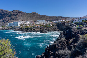 Obraz premium View of Los Gigantes Tourist City in Tenerife, Canary Islands, Surrounded by Ocean, Rocky Cliffs, and Vacation Architecture under the Bright Summer Sky