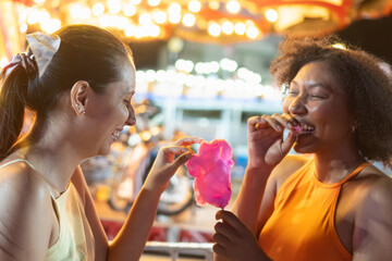 Friends enjoying cotton candy at night carnival