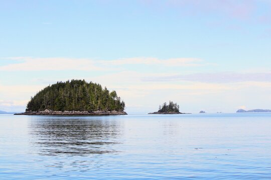 A beautiful seascape view of islands floating among a calm see during a summer day in the Broughton Archipelago, in British Columbia, Canada