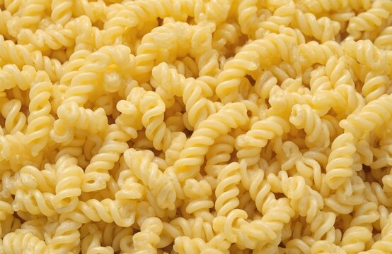 Close-up of fusilli pasta on white background. Soft, fluffy texture, vibrant yellow hue in elegant spiral pattern. Dry, uncooked, isolated, Italian food.