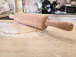 Fresh dough, rolled out with a rolling pin on a floured surface, ready for baking. Food concept