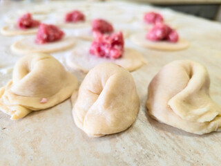 Round raw dumplings on the table, sprinkled with flour and rolled before filling with home-made meat. Traditional process of making Russian dumplings. Step-by-step overview of the cuisine Food concept