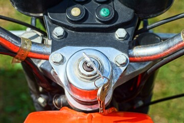 Fototapeta premium front of shiny bolted handlebar with one iron chromed small security key inserted into ignition of old retro industrial motorcycle