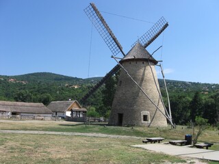 windmill in the village,The image features a traditional windmill with a stone base and wooden...