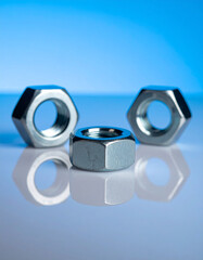 Group of shiny metal nuts on blue surface.